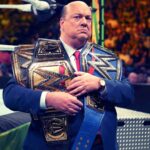 Paul Heyman segurando cinturões de Roman Reings