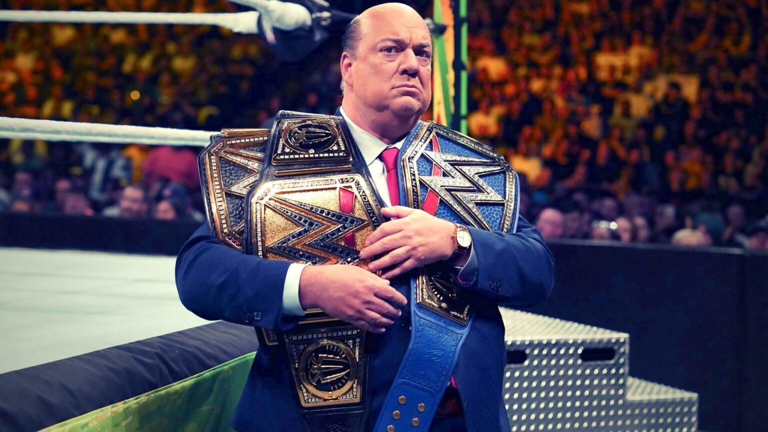 Paul Heyman segurando cinturões de Roman Reings