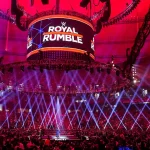 Arena lotada com palco iluminado e telão do Royal Rumble antes do início do evento — imagem ilustrando todos os vencedores do Royal Rumble.